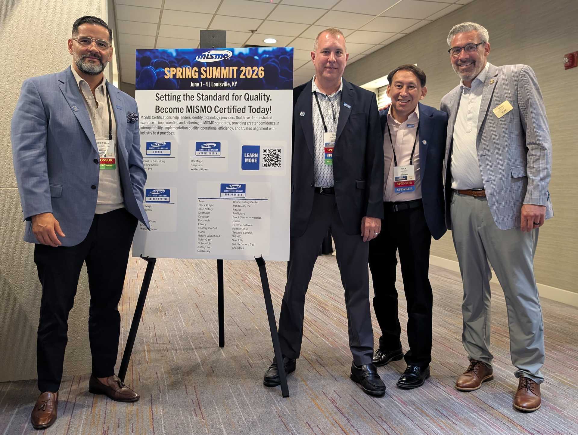 Four mortgage-industry professionals beside a MISMO certification display at the MISMO 2026 Spring Summit in Louisville, Kentucky.